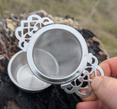 Elegant stainless steel tea strainer with lace handle and drip tray