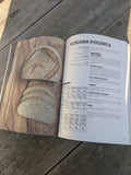 Open cookbook on a wooden surface with a recipe for golden polenta sourdough Kate Downham