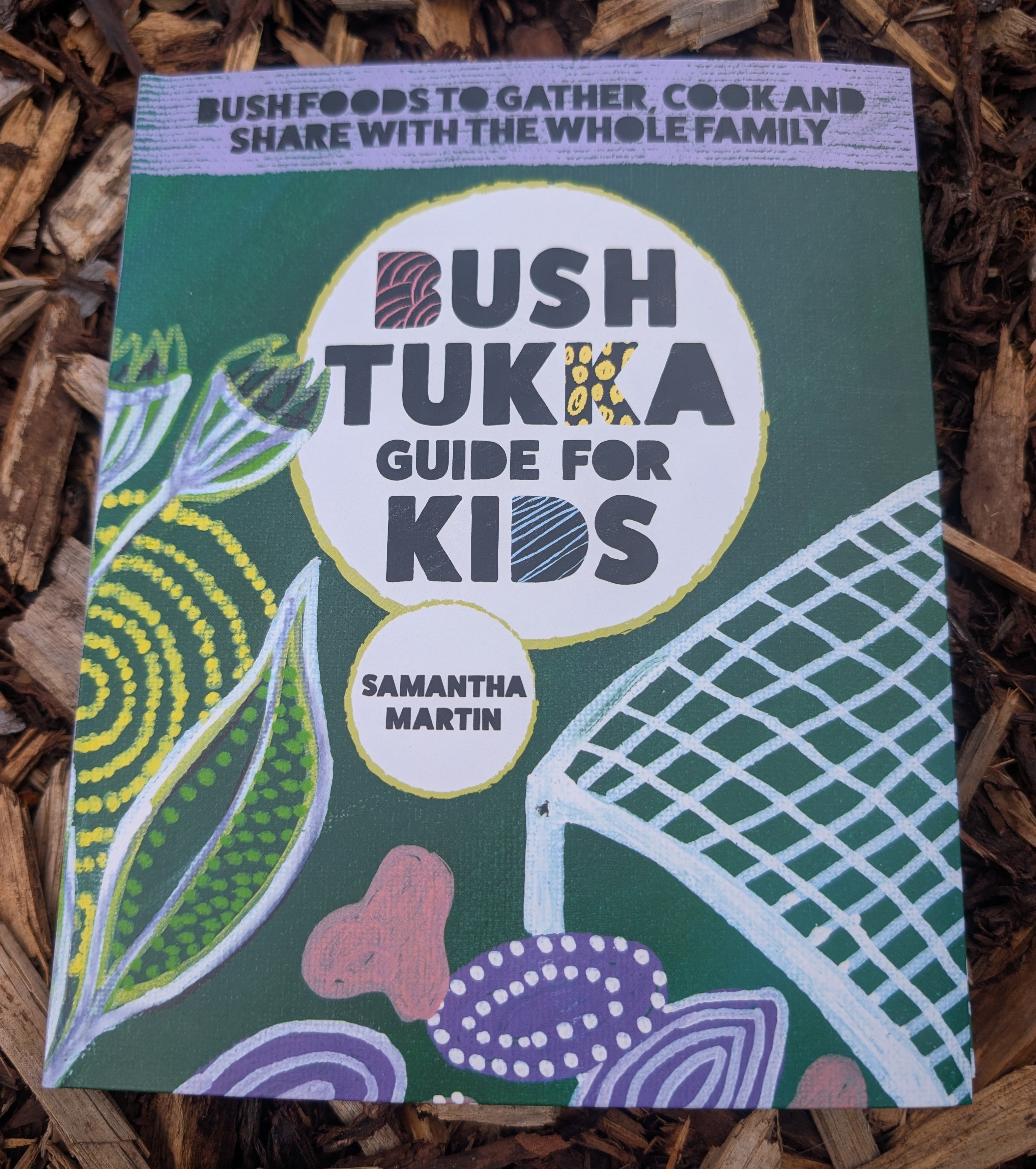 Book titled 'Bush Tukka Guide for Kids' by Samantha Martin on a wooden surface.