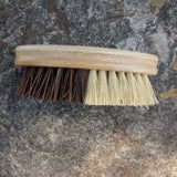 Double-sided brush with wooden handle on a stone surface