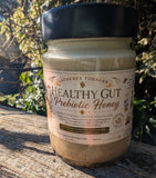 Jar of 'Healthy Gut Prebiotic Honey' on a wooden surface with a natural background