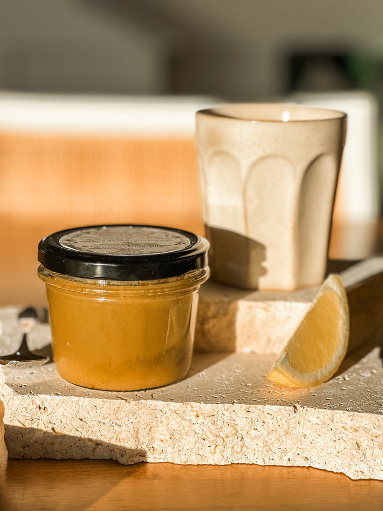 Jar of honey with a black lid on a wooden surface with a blurred background