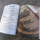 Open book showing a recipe for rye bread on a wooden surface