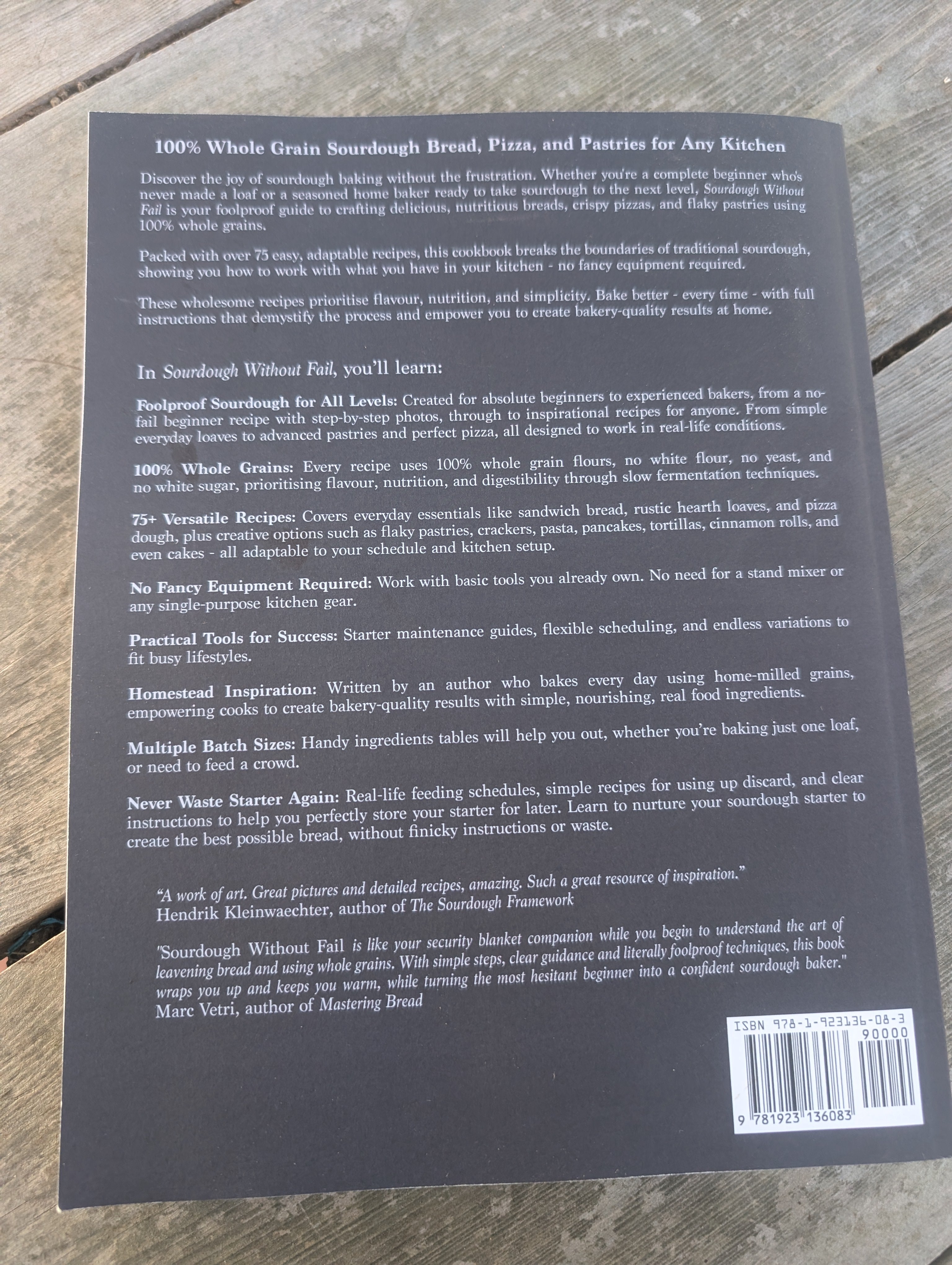 Back cover of sourdough without fail book with text and a barcode on a wooden surface