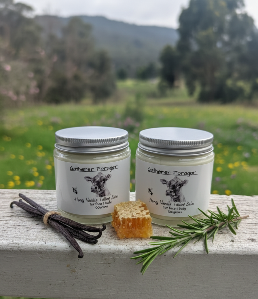 Two jars of 'Gatherer Forager' honey vanilla lotion bars on a wooden surface with vanilla beans, honeycomb, and rosemary in a natural setting. Main image